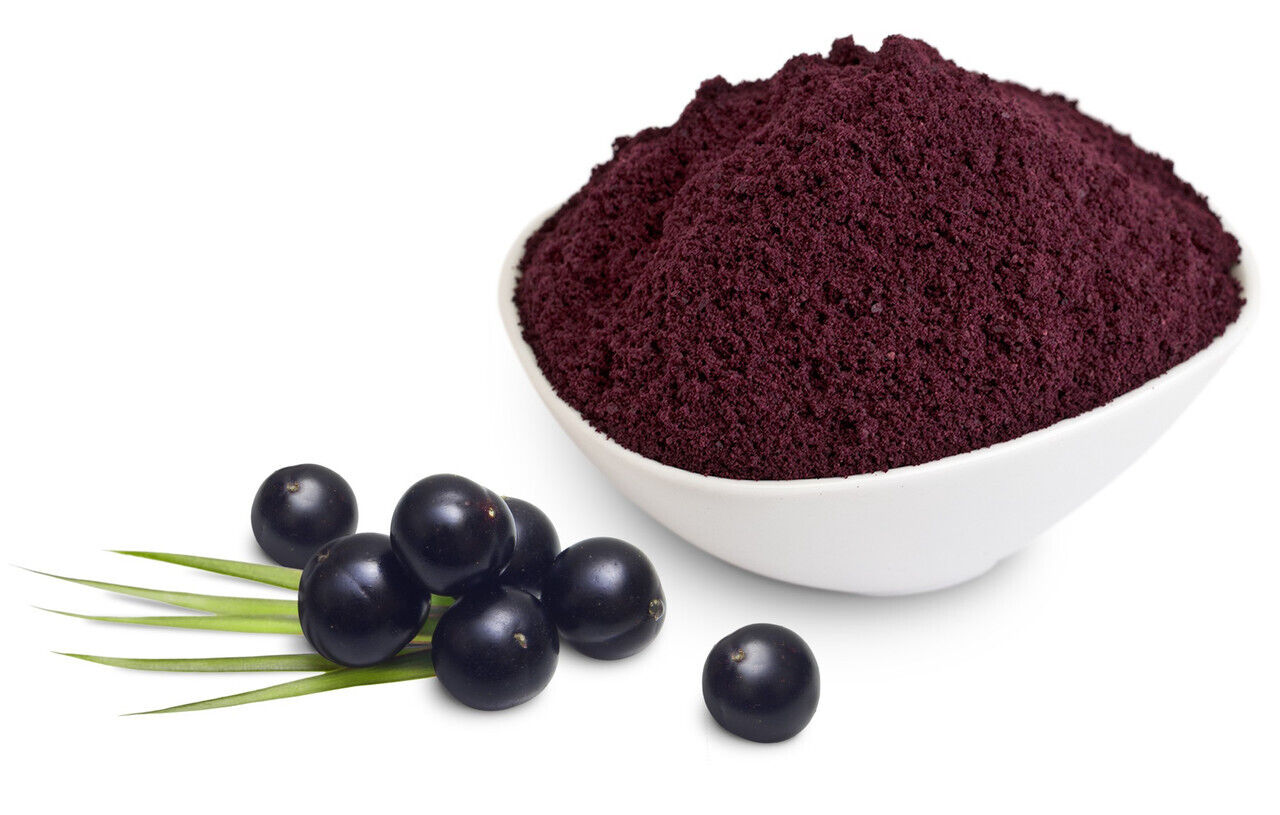 A bowl of organic acai powder next to several fresh acai berries on a white background.